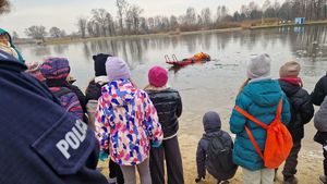 Dzieci obserwują strażaka wyciągającego z wody poszkodowanego.