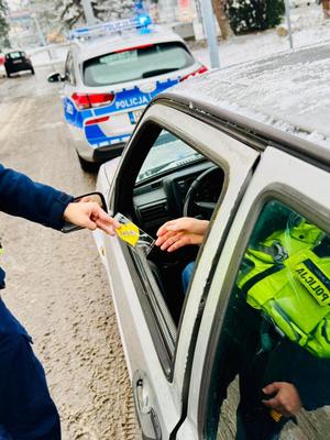 Policjant daje kierującemu zapachową zawieszkę.