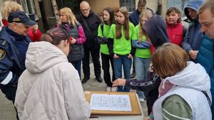 Grupa uczestników gry miejskiej wykonujących zadanie przy budynku Straży Miejskiej.