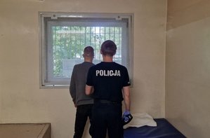 Policjant stoi z zatrzymanym mężczyzną.