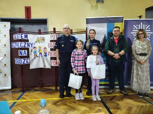 Nadkomisarz Rafał Adamek I Zastępca Komendanta Powiatowego Policji w Pabianicach oraz organizatorzy konkursu i jury pozują do zdjęcia z laureatami zmagań.