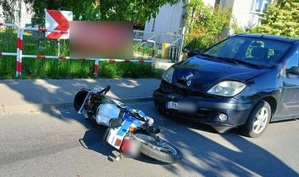 Miejsce zdarzenia drogowego na którym widać leżący motorower i uszkodzoną osobówkę.