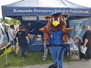 Maskotka pabianickiej policji, w tle stoisko mundurowych.