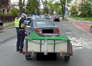 Policjant stojący przy pojeździe biorącym udział w zdarzeniu drogowym.