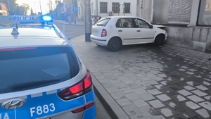 Miejsce zdarzenia na którym widać białą skodę, która uderzyła w budynek i policyjny radiowóz.