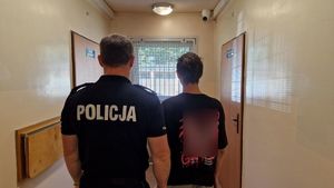 Umundurowany policjant z zatrzymanym mężczyzną.