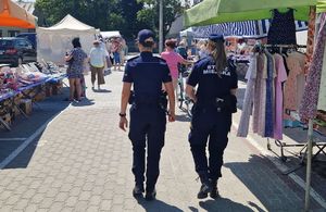Policjantka i strażniczka miejska na targowisku pomiędzy stoiskami.