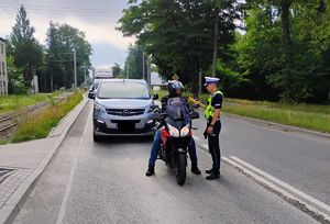 Policjant bada motocyklistę alkomatem.