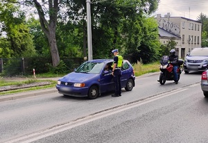 Policjant bada kierującego samochodem alkomatem.