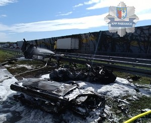Miejsce zdarzenia drogowego, na którym widać fragmenty rozbitego pojazdu. W lewym górnym rogu gwiazda pabianickiej policji.