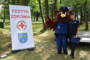 Policjantka wraz z maskotką sową. W tle napis festyn rodzinny.