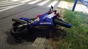 Niebieski motocykl leżący na drodze.