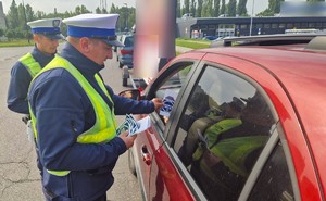 Policjant wręcza kierującemu materiały informacyjne dotyczące kampanii Mistrzu, zwolnij.