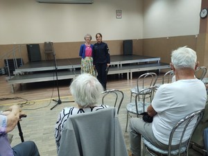 Policjantka stojąca obok seniorki na spotkaniu w klubie seniora.