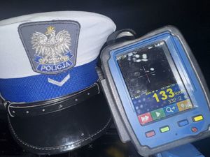 Ręczny miernik prędkości, obok niego policyjna czapka.