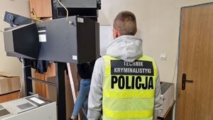 Policjant stoi przy urządzeniu do fotografowania zatrzymanych.