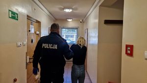 Umundurowany policjant stoi z zatrzymaną kobietą.