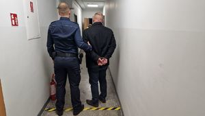 Umundurowany policjant stoi z zatrzymanym mężczyzną.