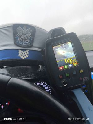 Ręczny miernik prędkości obok policyjnej czapki.