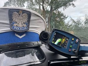 Ręczny miernik prędkości obok policyjnej czapki.