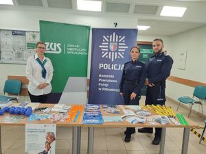 Stoisko profilaktyczne, przy którym stoją policjanci i pracownica miejscowego Zakładu Ubezpieczeń Społecznych.