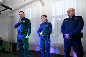Dwóch policjantów i policjantka. Policjant stoi z mikrofonem