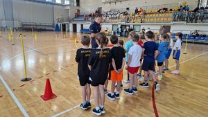 Zawodnicy zgrupowani przed policjantem omawiającym sposób pokonywania toru przeszkód.