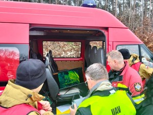 Służby zgromadzone przy aucie. Mężczyźni wpatrują się w ekran laptopa.