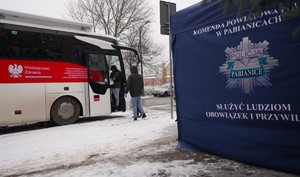 Policyjny namiot, za nim krwiobus i osoby czekające na wejście do niego.