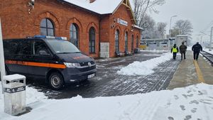 Policjant, funkcjonariusz Służby Ochrony Kolei i żołnierz idą ścieżką na dworcu obok torów kolejowych.