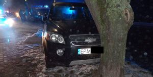 Samochód rozbity na drzewie, w tyle policyjne radiowozy i funkcjonariusze.