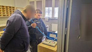 Policjant bada alkomatem nietrzeźwego kierującego.