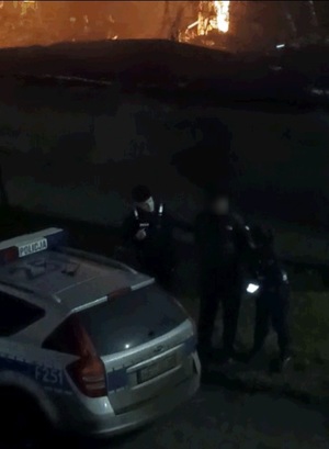Policjanci zatrzymują podpalacza w miejscu zdarzenia.
