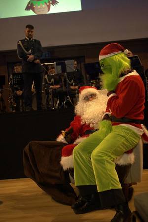 Grinch siedzi na kolanach Świętego Mikołaja.