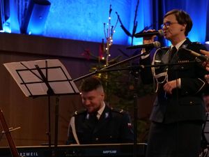 Policjantka śpiewająca na scenie. Za nią policjant.