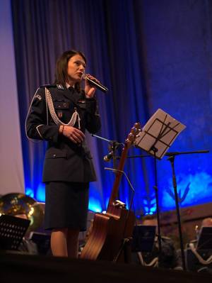 Policjantka śpiewająca na scenie.