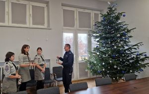 Trzy harcerki przekazują światełko Komendantowi