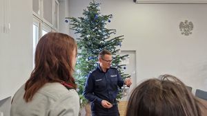 Komendant trzymający w rękach światełko. W tle choinka.