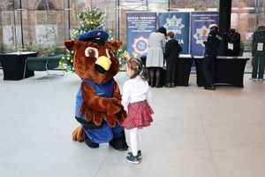 Policyjna maskotka bawi się z małym dzieckiem.