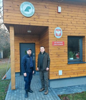 Strażnik Leśny i Policjant na tle budynku Leśnictwa Mianów.