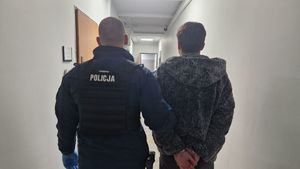 Umundurowany policjant stoi z zatrzymanym mężczyzną.