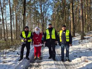 Policjanci stoją z Mikołajem w lesie.