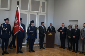 Samorządowcy stoją przy mównicy obok pocztu sztandarowego.