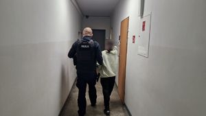 Policjant idzie z zatrzymaną kobietą.