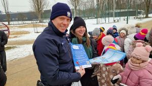 Policjant rozdaje materiały informacyjne uczestnikom spotkania.