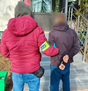 Nieumundurowany policjant stoi z zatrzymanym mężczyzną.