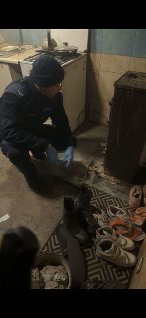 Policjant pomaga rozpalić w piecu.