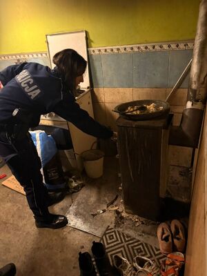 Policjantka pomaga rozpalać w piecu.