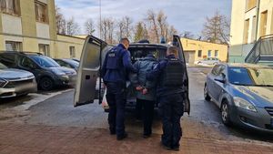 Policjanci umieszczają poszukiwanego w radiowozie.