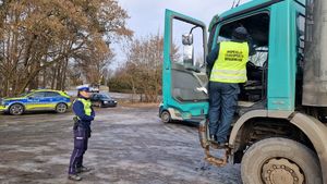 Policjantka stoi przy ciężarówce kontrolowanej przez funkcjonariusza Inspekcji Transportu Drogowego.